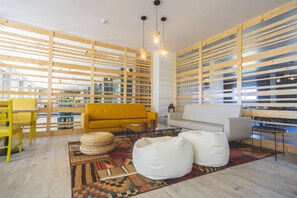 Una sala moderna con un sofá amarillo, pufs blancos y un tapete estampado.