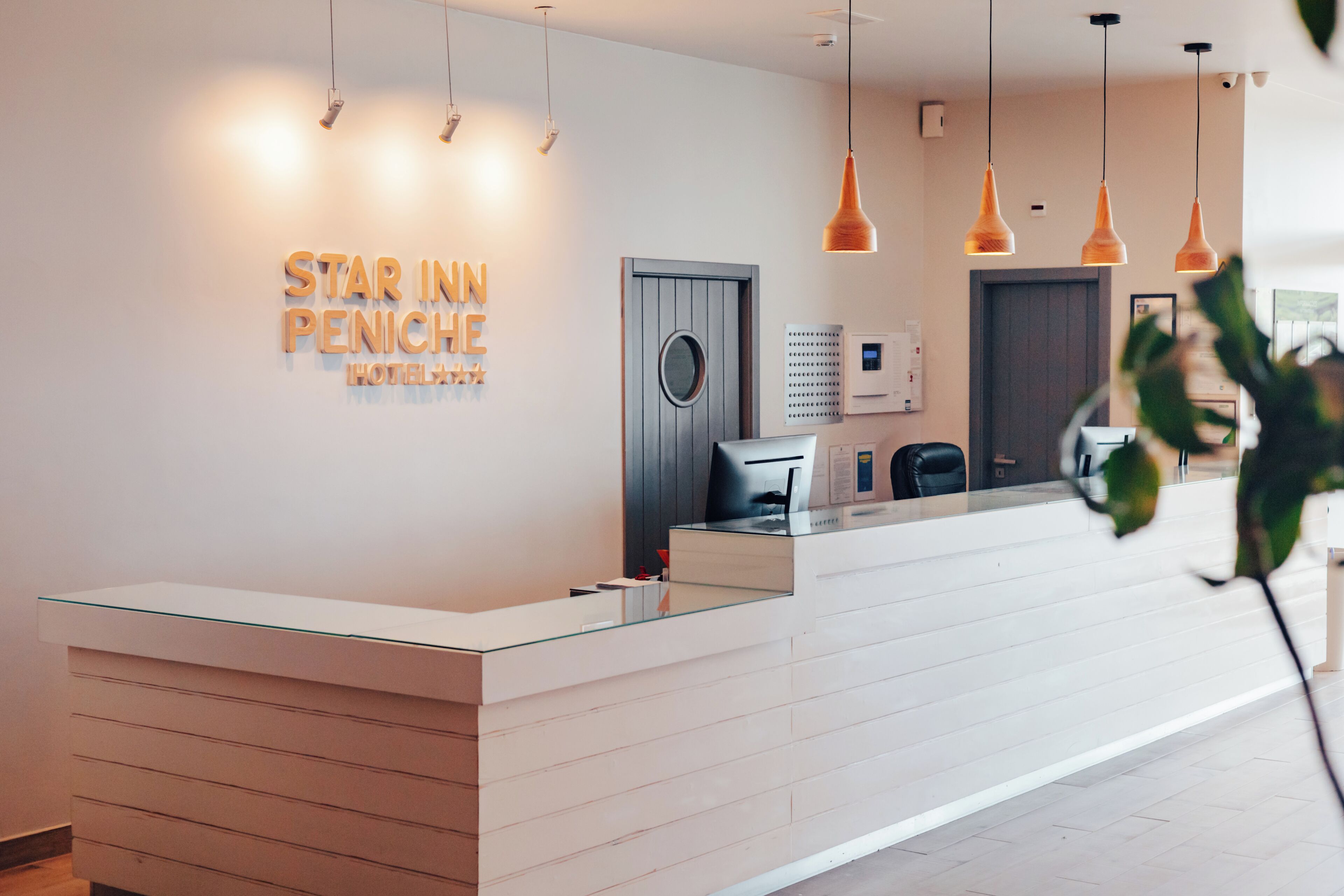 Una recepción de hotel de diseño moderno, una pantalla digital y un cartel que dice 'STAR INN PENICHE HOTEL'.
