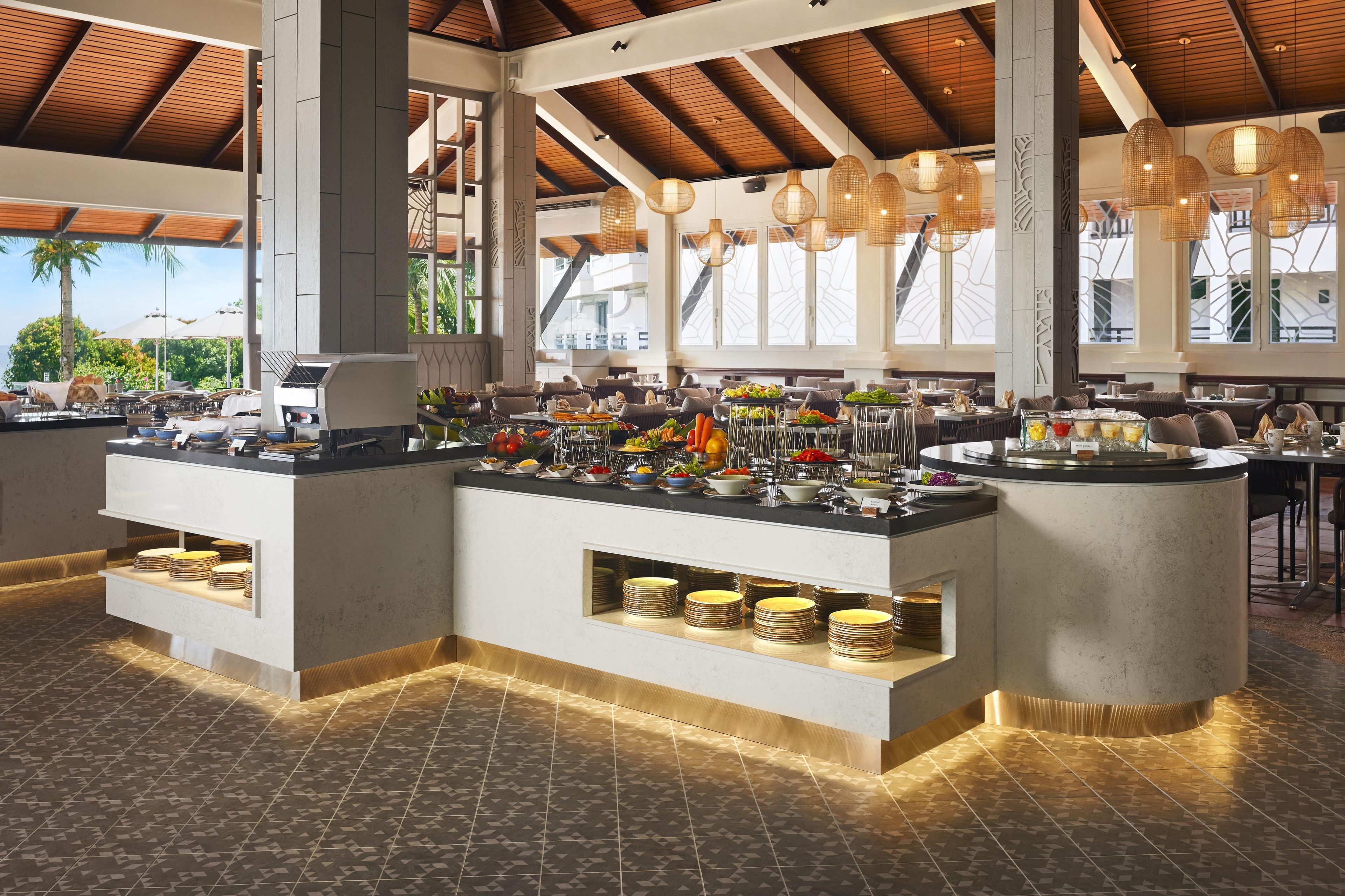A buffet setup with various food items and a seating area with tables and chairs.