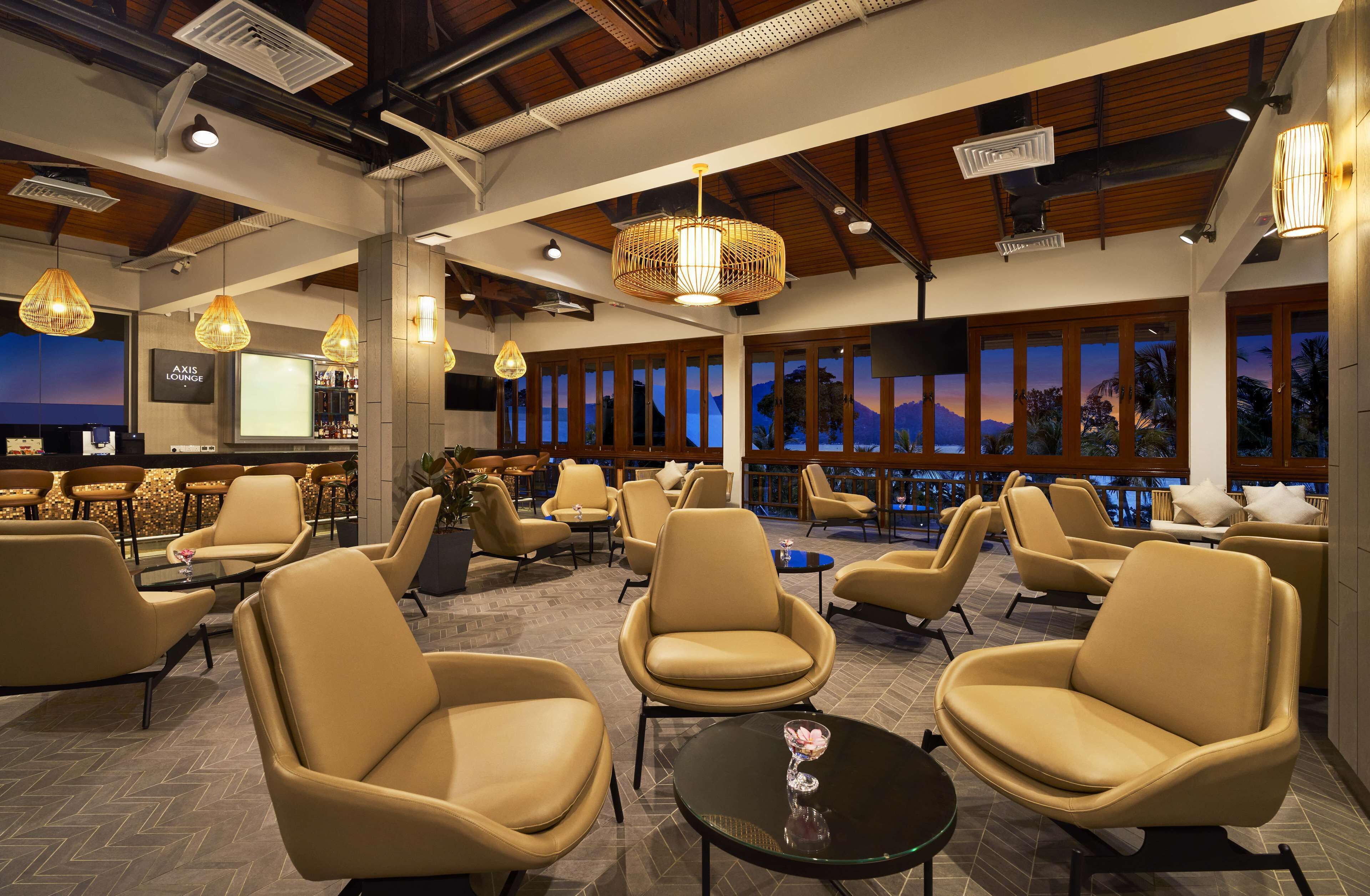 A modern lounge with leather chairs, a bar area, and large windows offering a view of the mountains.
