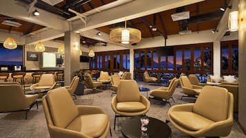A modern lounge with leather chairs, a bar area, and large windows offering a view of the mountains.