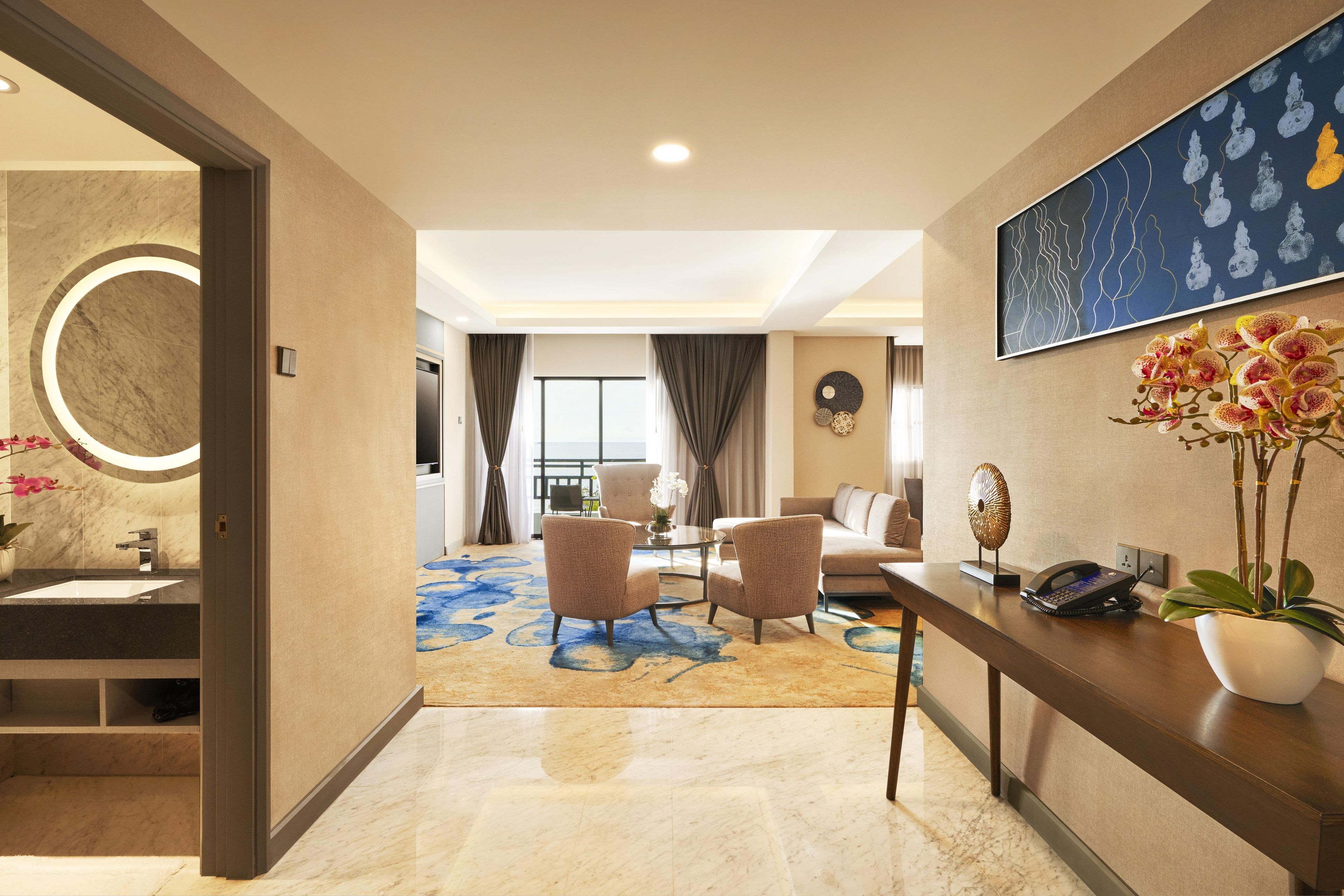 A hotel lobby with a reception desk, seating area, and a view to the balcony.