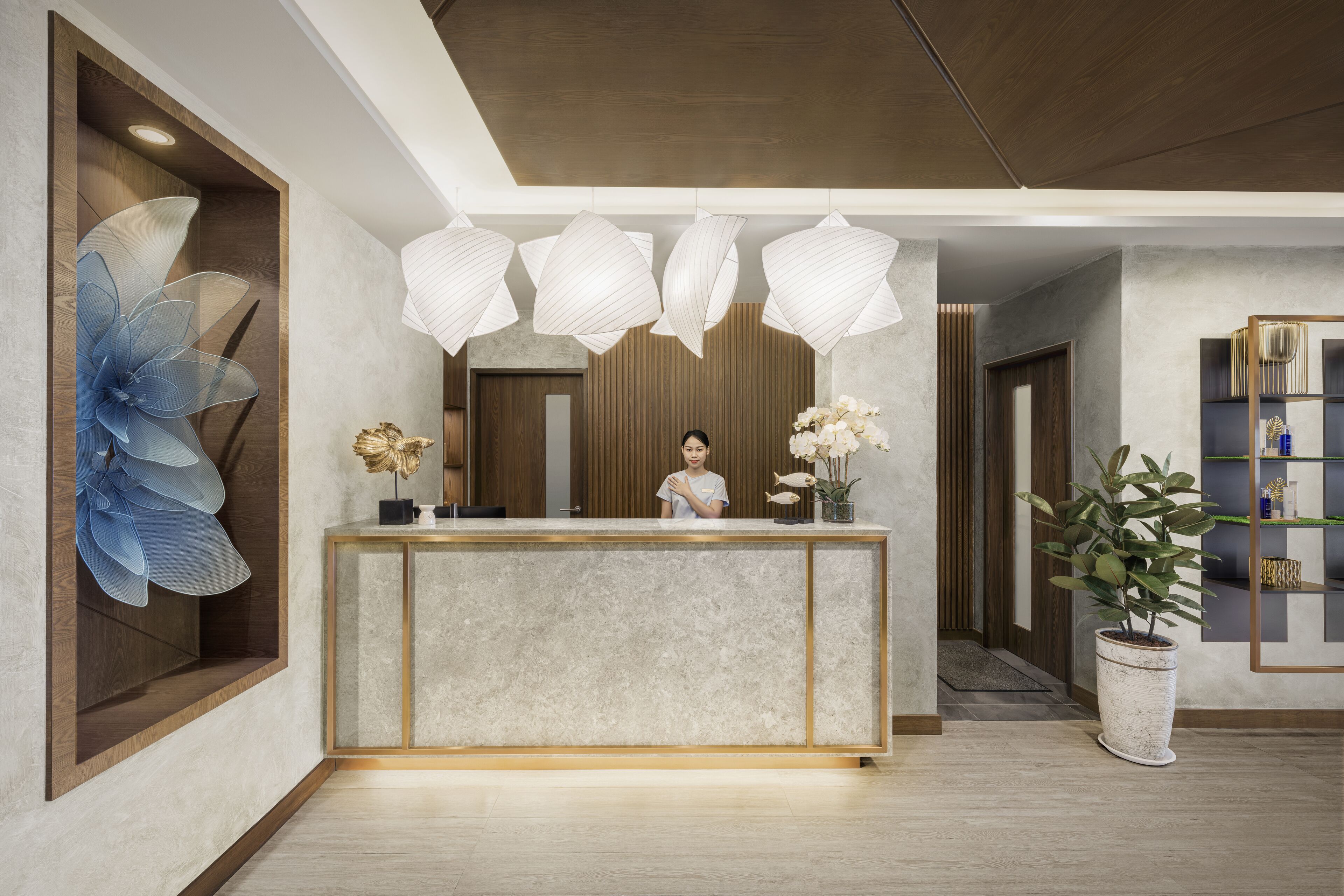 A reception desk with a modern design, a large abstract floral artwork on the wall, and a potted plant to the right.