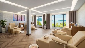 Een moderne hotelkamer met een groot raam dat uitzicht biedt op een mooi panorama, een massagestoel, een klein tafeltje met voorzieningen en een receptiebalie.
