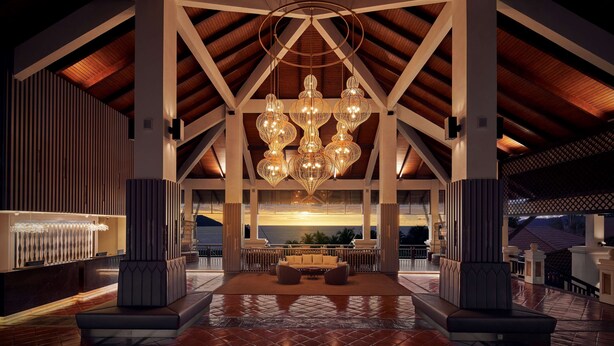 Een ruime lobby met een hoge plafond, een centraal zithoek en een groot raam met uitzicht op zee.