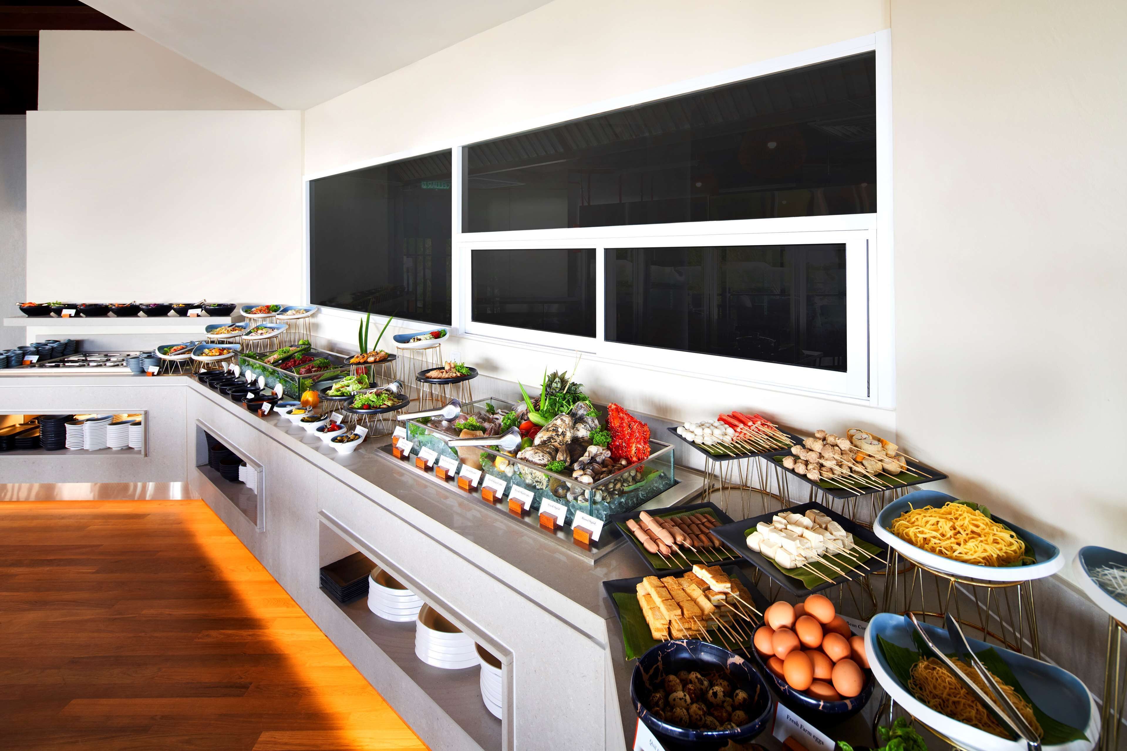 A buffet setup with various food items and a large window in the background.