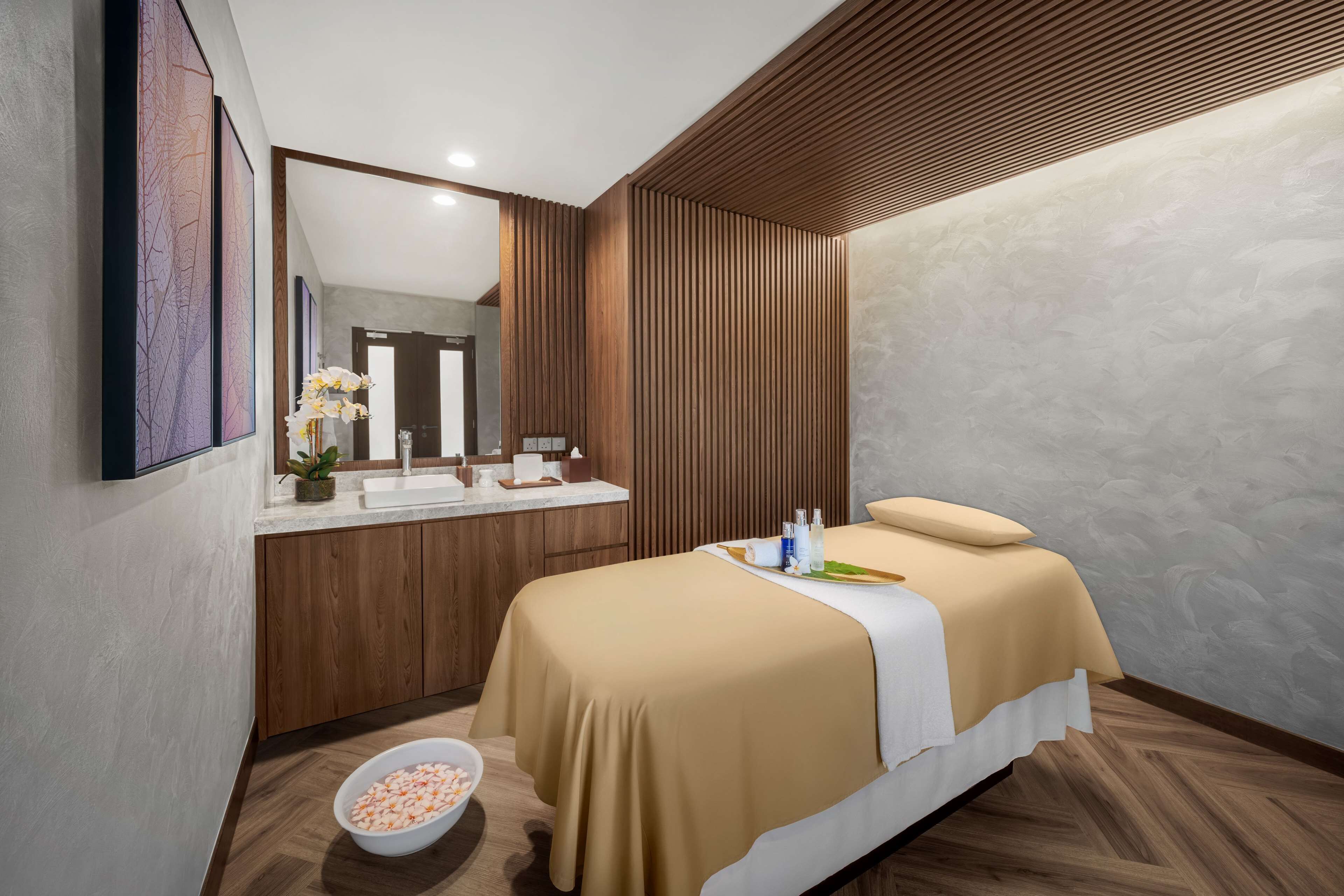 A modern bedroom with a wooden vanity, a large bed, and a bowl of snacks on the floor.