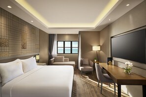 Een hotelkamer met een bed, een bureau, een stoel, een televisie en een raam met uitzicht op zee.