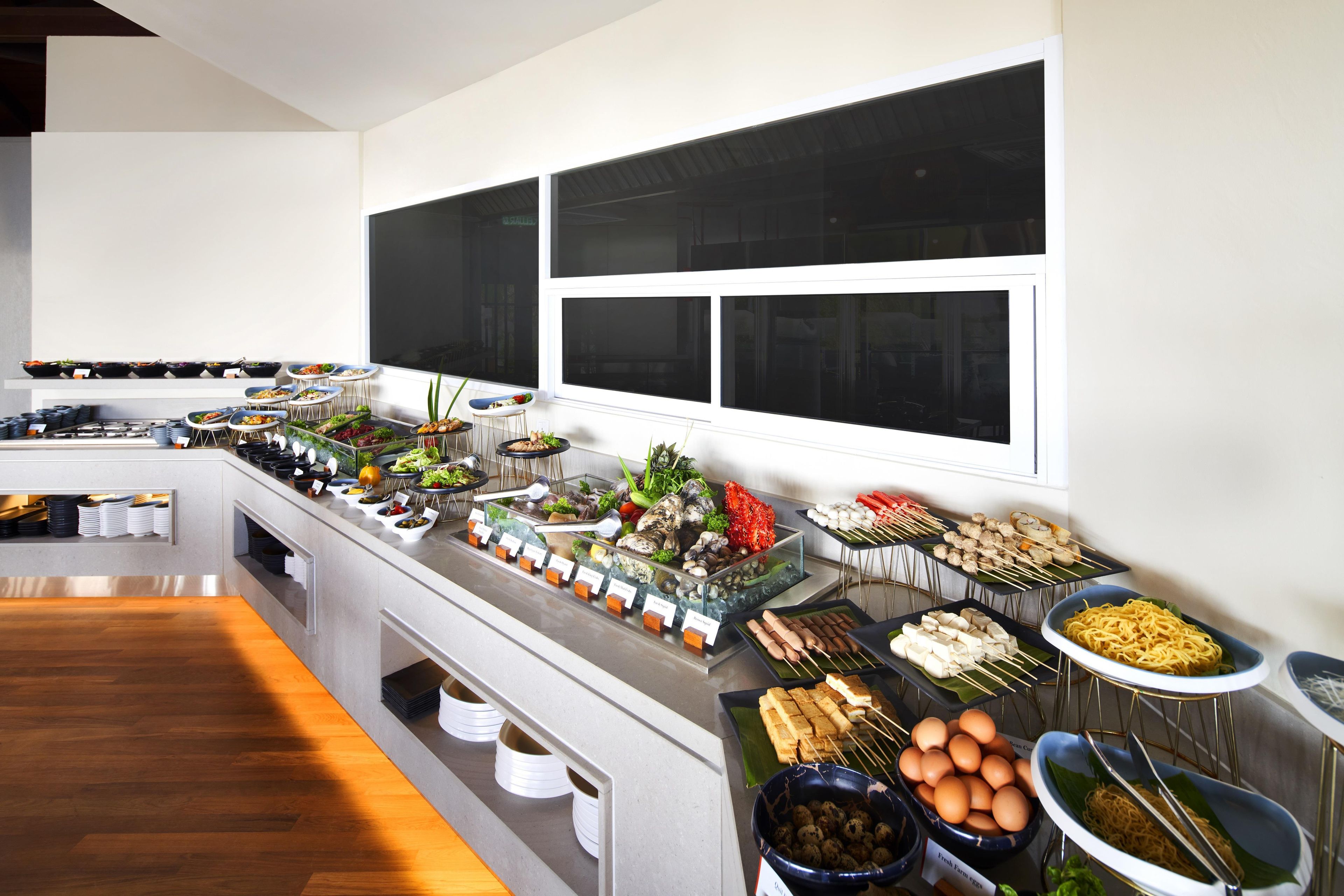 A buffet with various food items and a seating area with chairs.