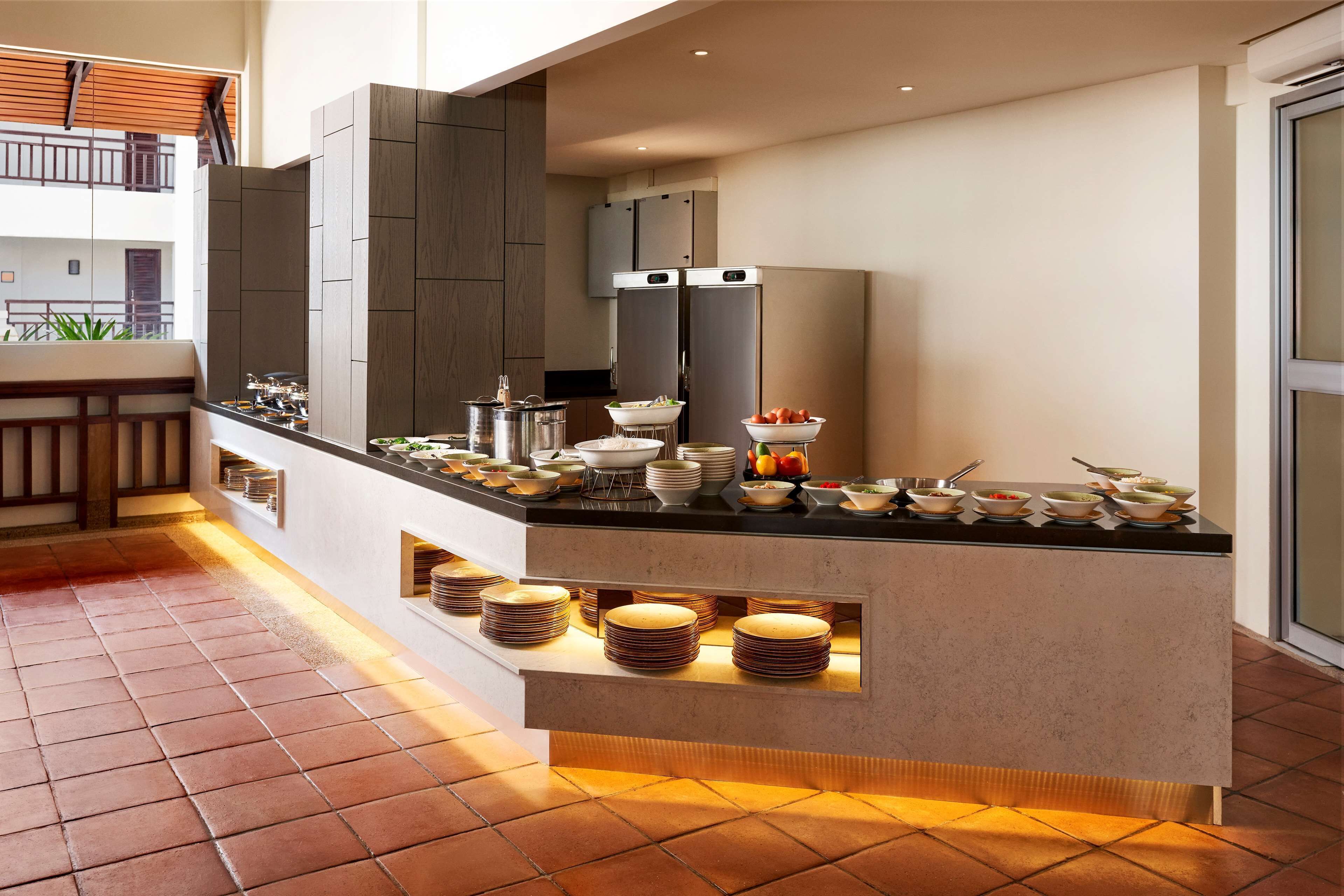 A modern kitchen with a central island, built-in appliances, and a variety of dishes and utensils.