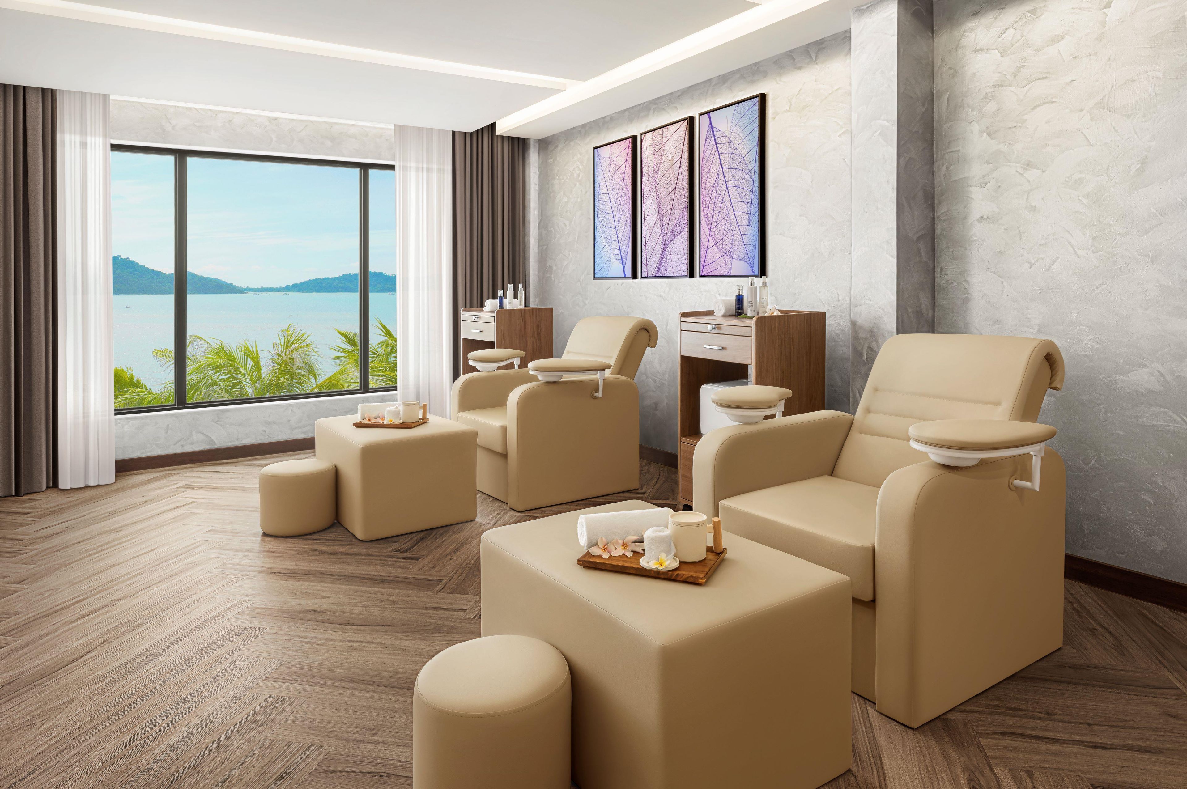 A spa room with massage chairs, a wooden desk, and a large window with a view of the water.