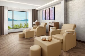 Een spa-ruimte met massagestoelen, een houten bureau en een groot raam met uitzicht op het water.