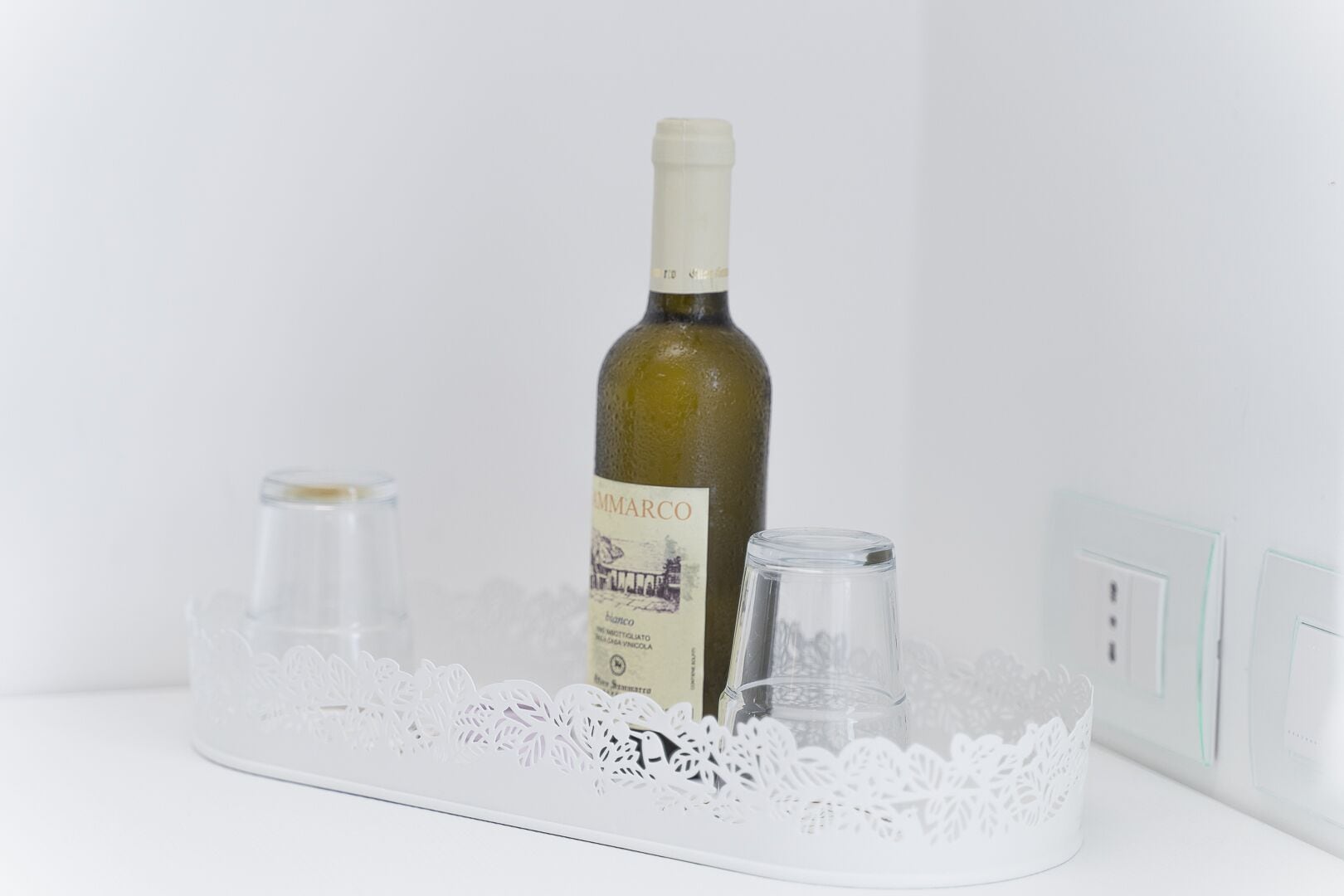 A wine bottle labeled "VIGNI DOC" on a white tray with two glasses.