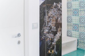 A bathroom with a tiled wall, a white sink, and a door with a handle. - Hotel Miramare (Maiori)