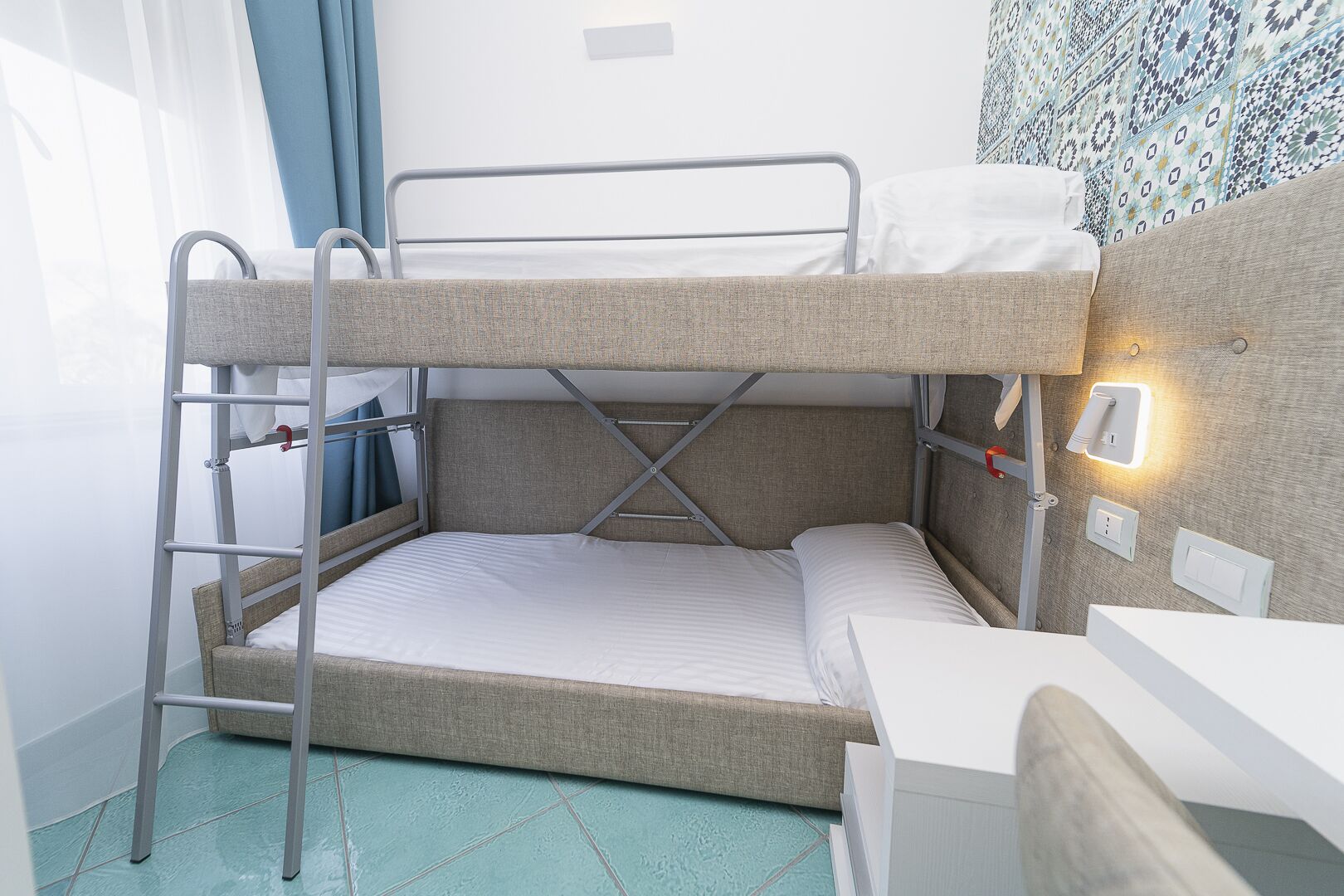 A bunk bed with a desk and a wall-mounted light.