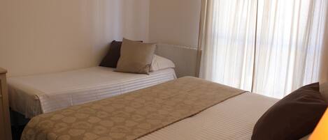 Hotellihuone, jossa on kaksi sänkyä, ja jokaisessa sängyssä on kuviollinen peitto ja tyynyjä.