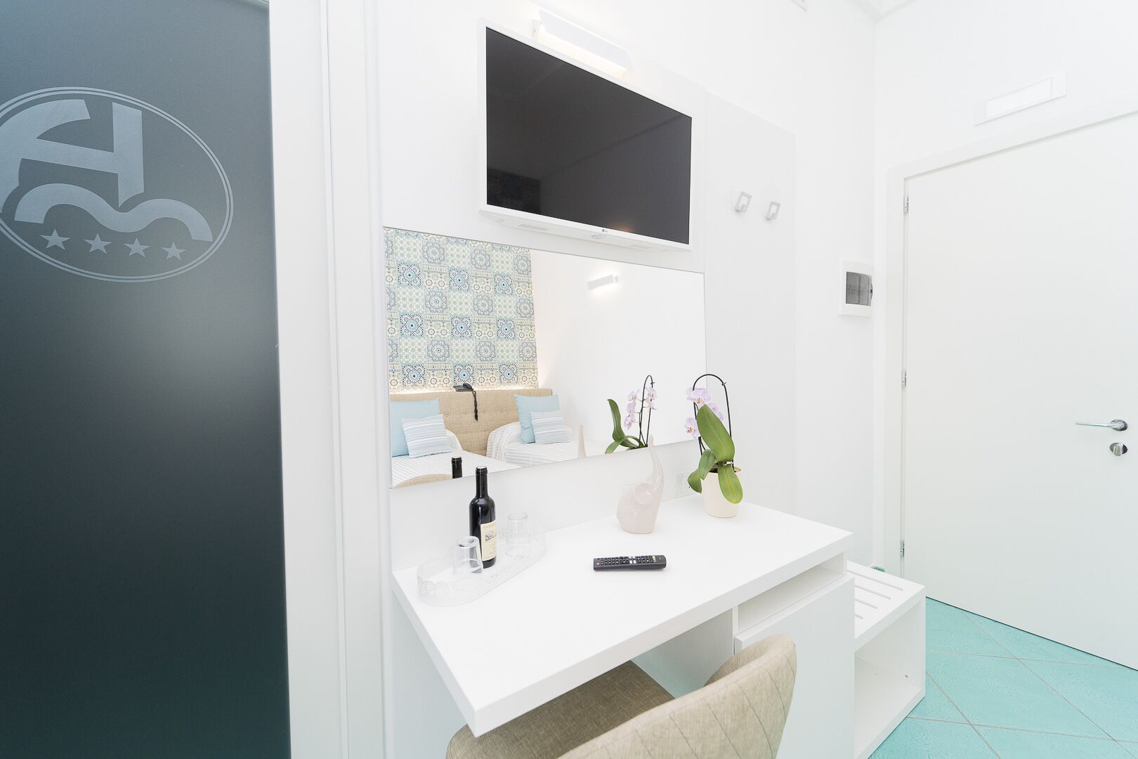 A modern bathroom with a white vanity, a mirror, a sink, and two potted orchids.