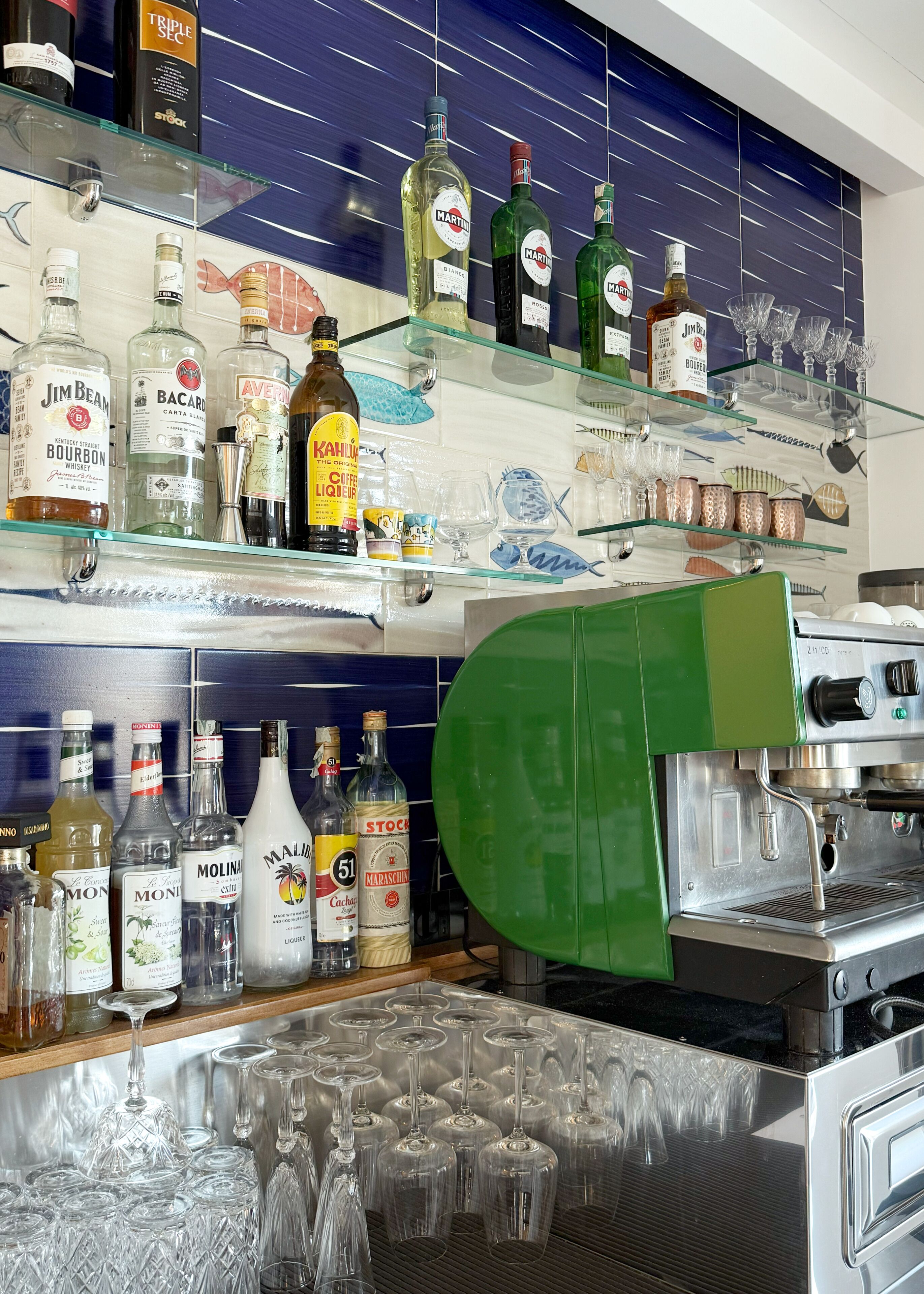 Zona de bar con estantes llenos de botellas de licor y vasos.
