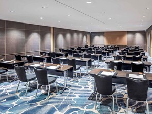 A conference room with rows of tables and chairs, a patterned carpet, and recessed ceiling lighting. - Fairmont Singapore (Singapore)