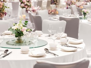 Une table dressée pour un événement formel, avec des nappes blanches, de la verrerie et un centre de table floral.