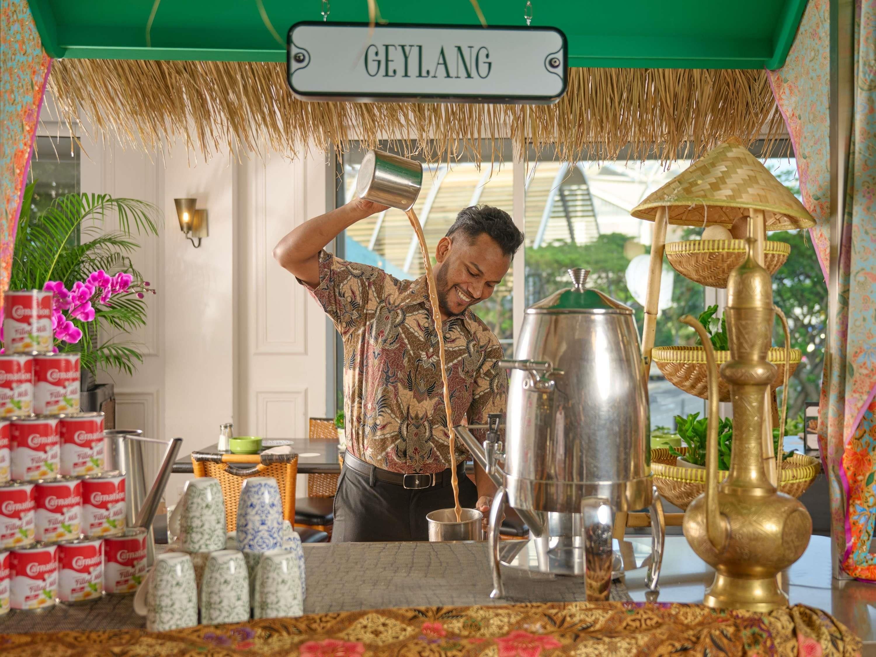 A traditional coffee station with a sign reading "GEYLANG" and a man pouring coffee into a cup.