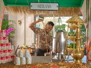 Una estación de café tradicional con un letrero que dice 'GEYLANG' y un hombre sirviendo café en una taza.