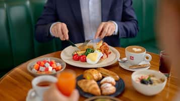A dining table with various breakfast items, including eggs, tomatoes, and croissants.