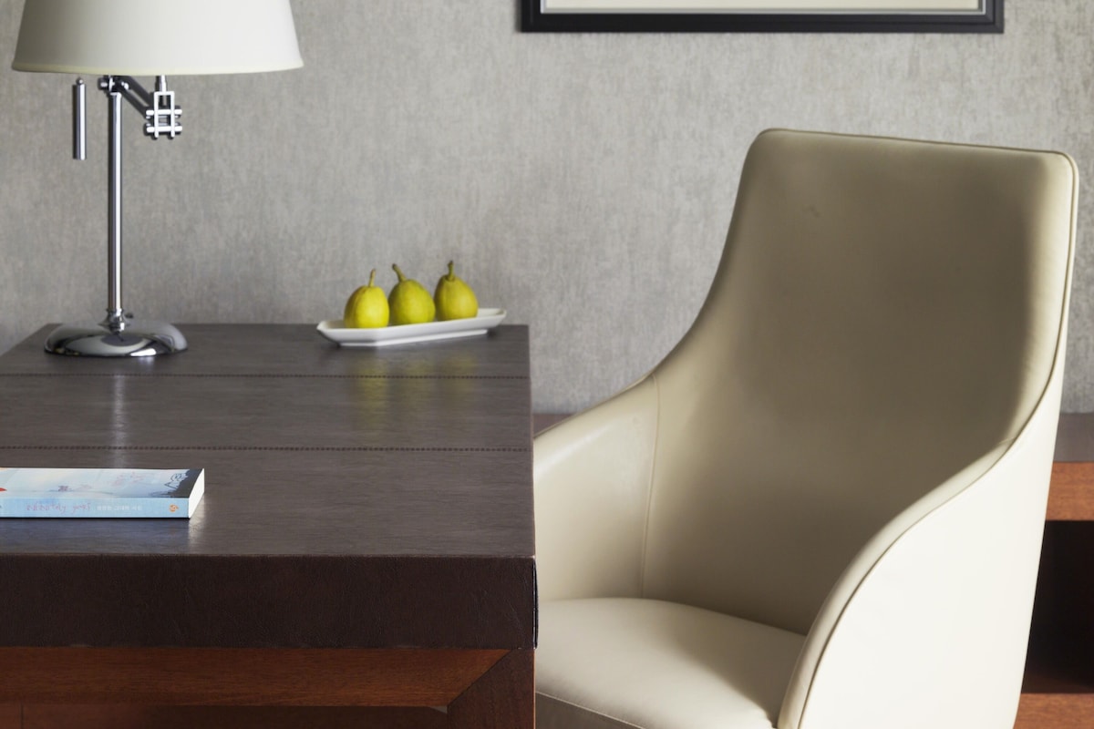 Een moderne kamer met een bureau, een lamp, een lijst met abstracte kunst en een stoel.