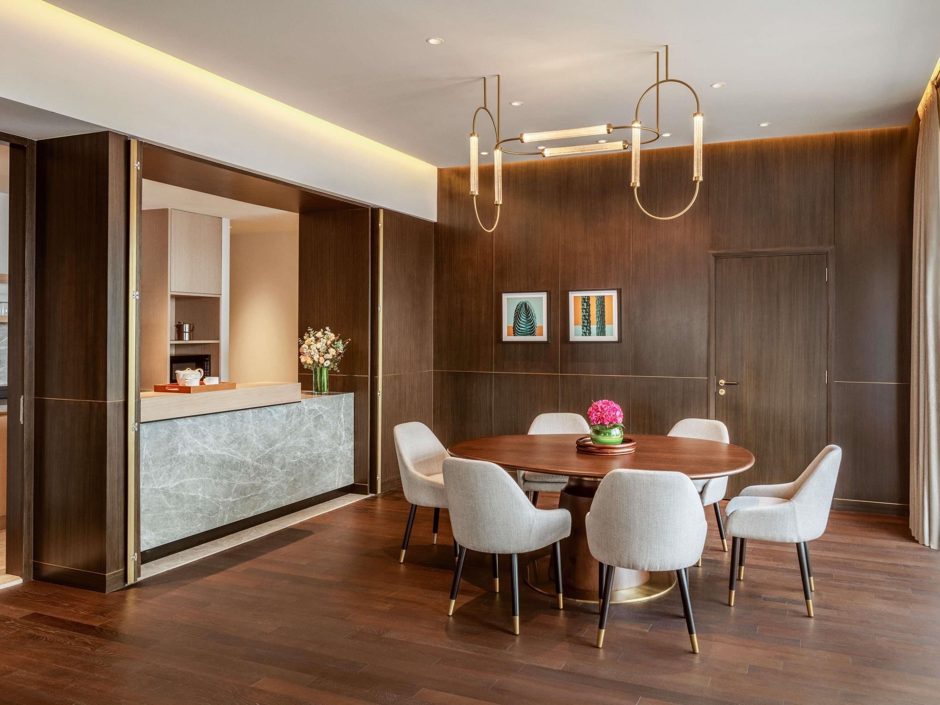 Un espace repas moderne avec une table ronde, six chaises et un vase central.