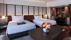 Habitación de hotel con dos camas, un escritorio, una silla, una cafetera y un minibar.