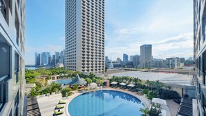 Un edificio de gran altura con zona de piscina que incluye tumbonas y un área de estar cubierta.