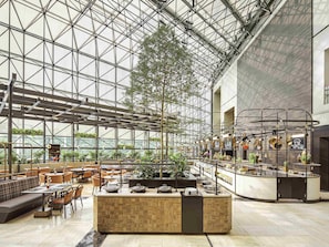 A spacious indoor area with a high ceiling, a central seating area with a long table, and a counter with various items.