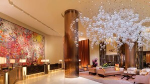 Un hall de hotel con mostrador de recepción, zona de estar e instalación decorativa grande en el techo.