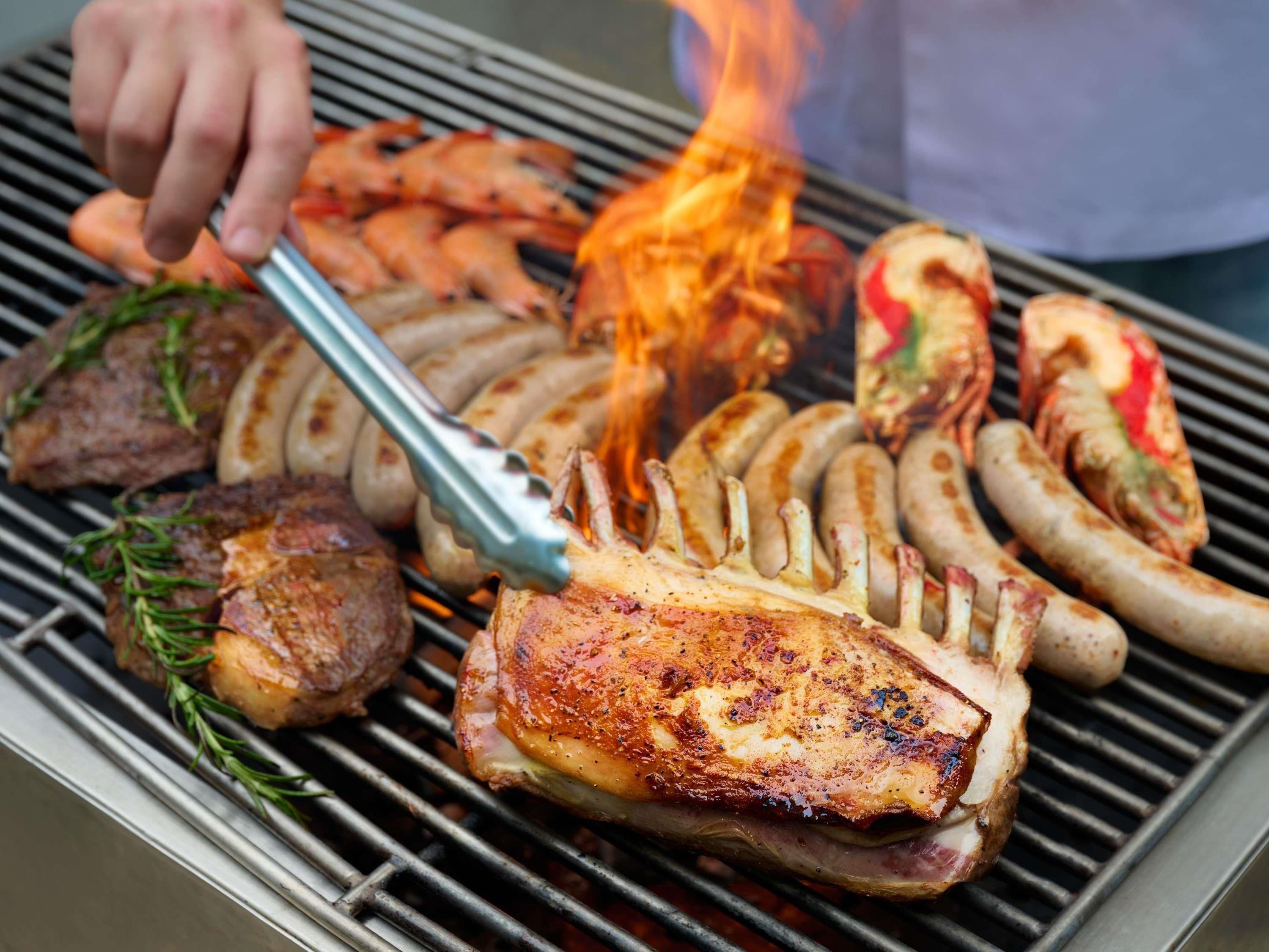 A grill with various meats and sausages being cooked.