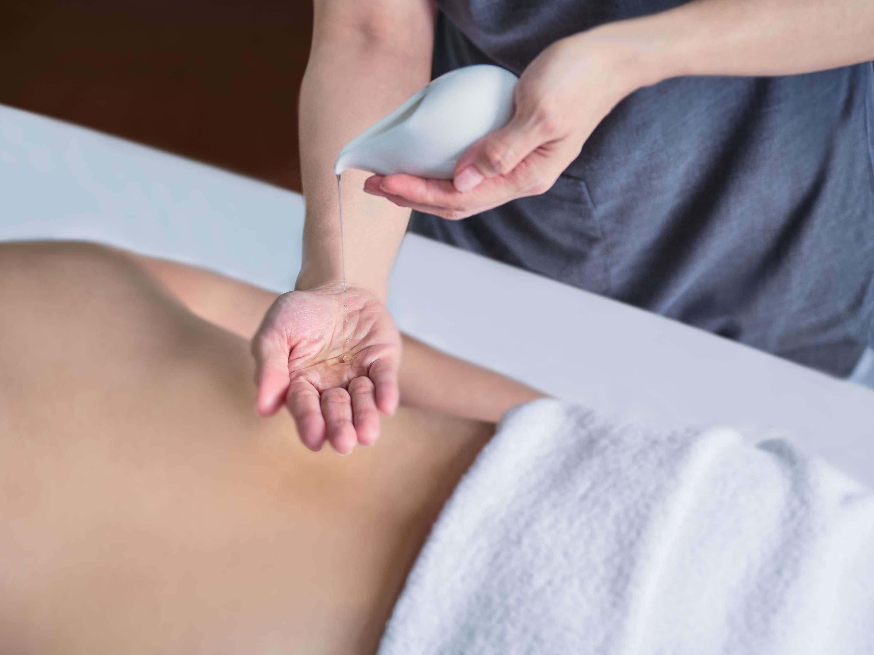 A person receiving a massage with a white towel covering their lower body.