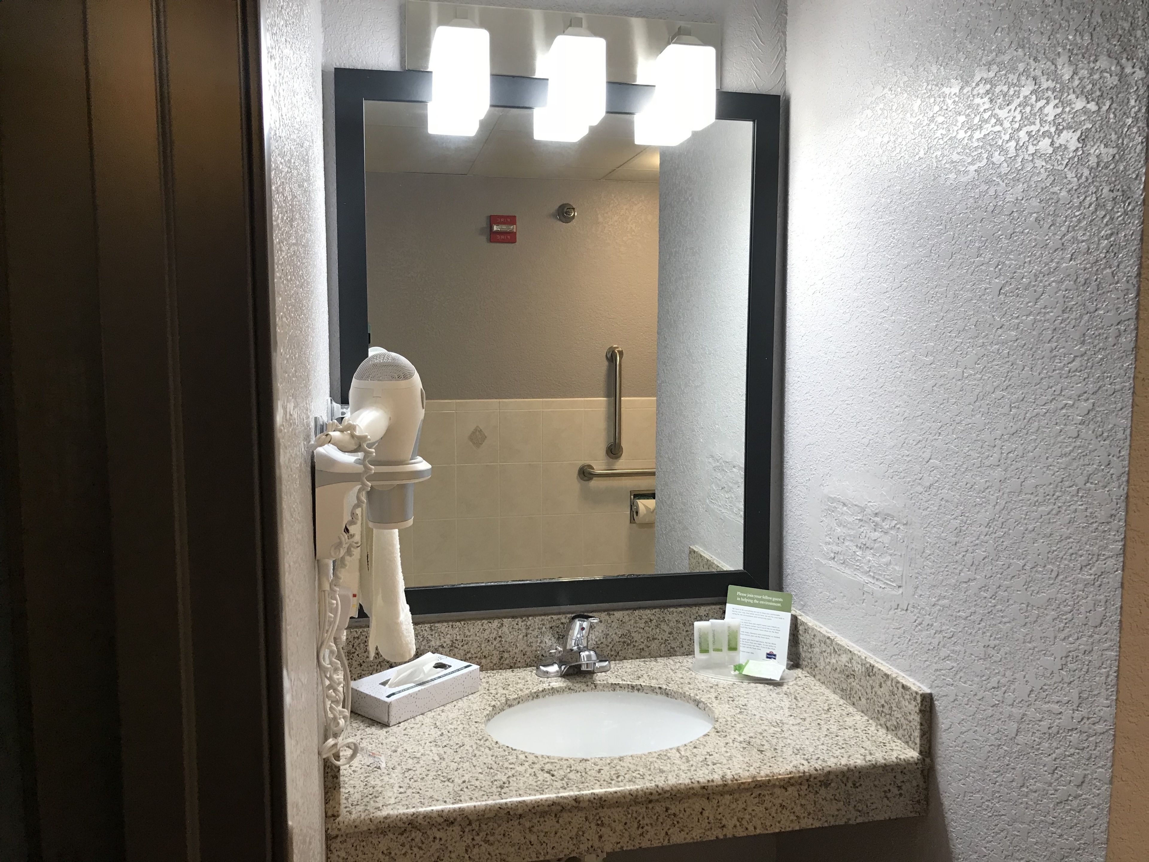 A bathroom with a white sink, a mirror, and a hand dryer.