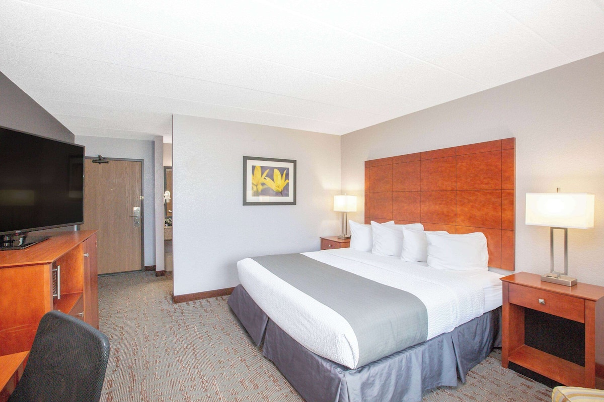A hotel room with a large bed, a television, a desk, and a nightstand with lamps.