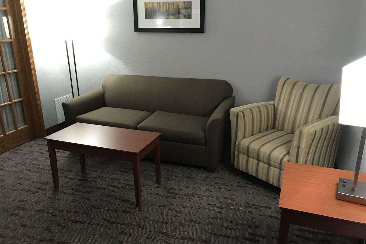 A room with a sofa, armchair, and a small table.