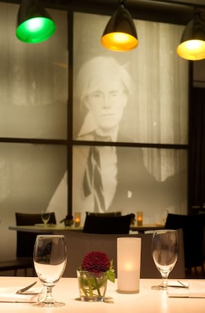A table with two wine glasses, a candle, and a vase with a flower. - Park Plaza Berlin (Berlin)