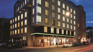 Een modern hotel met meerdere verdiepingen, grote ramen en een goed verlichte entree.