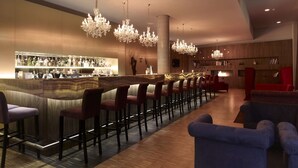 Een bar met een lange toonbank, diverse barkrukken en een open haard.