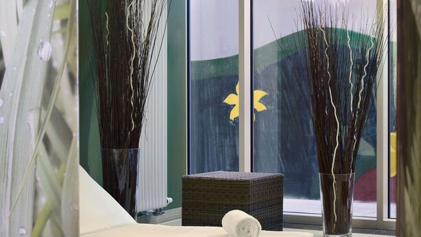Een spa-ruimte met twee rieten fauteuils, een groot raam en hoge decoratieve vazen.