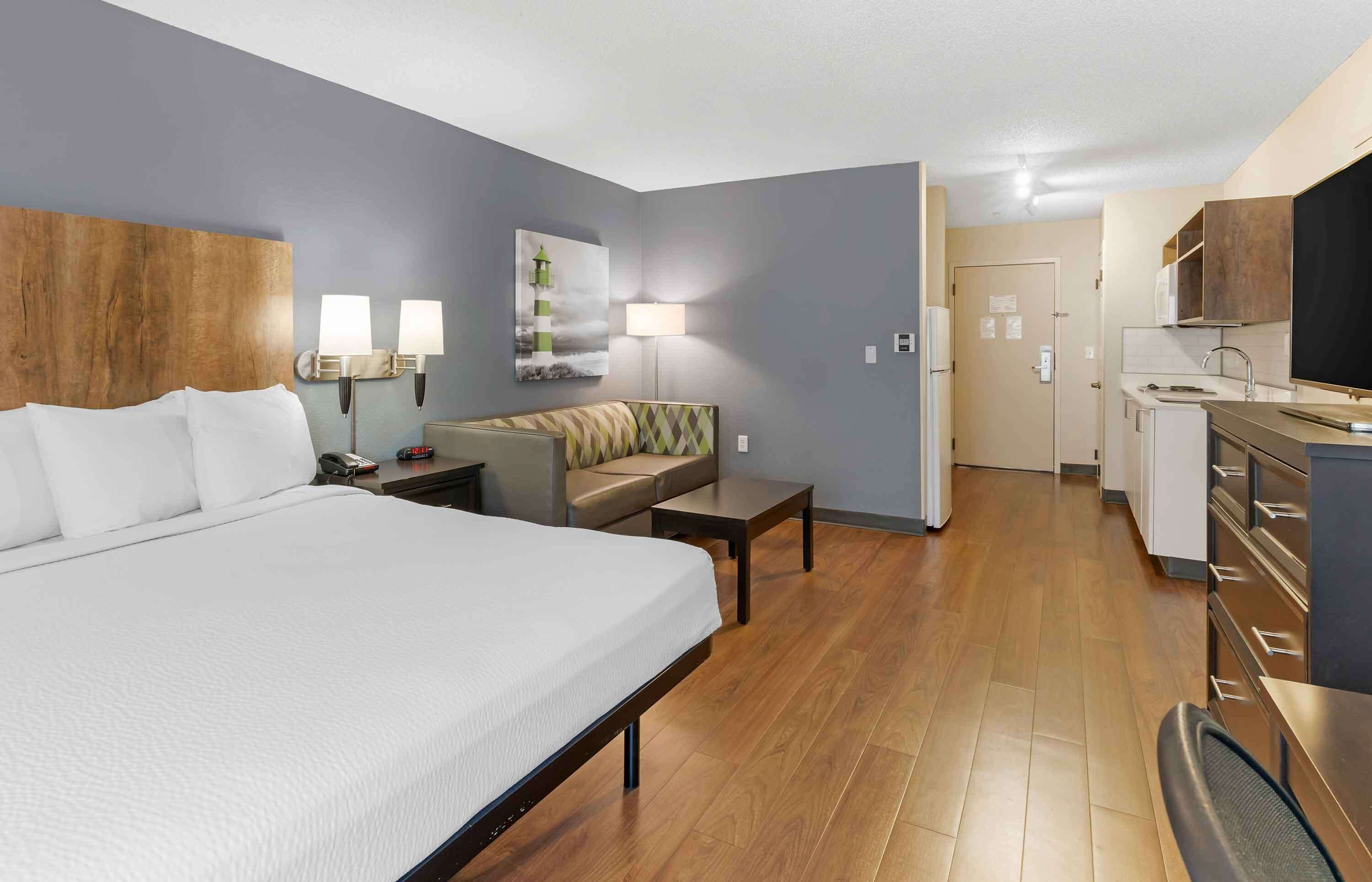 Habitación de hotel con una cama grande, un sofá, un escritorio y una kitchenette.