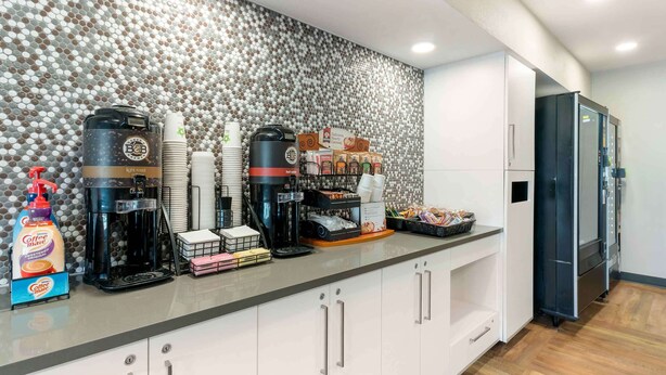 Ett modernt kök med en kaffestation, inklusive en kaffemaskin, koppar och en kaffebryggare.