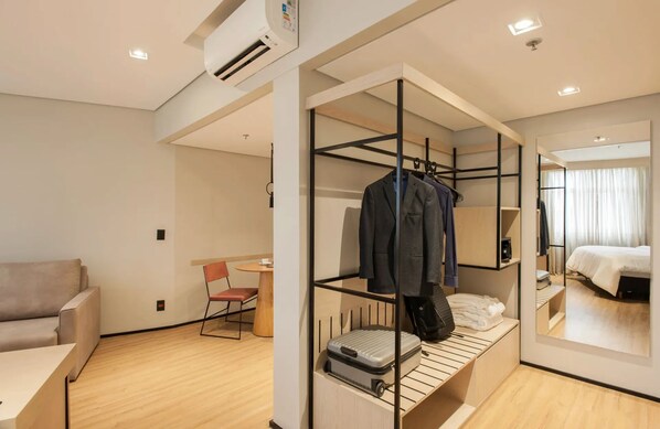 Una habitación de hotel moderna con una cama individual alta, un escritorio, una silla y una cama.