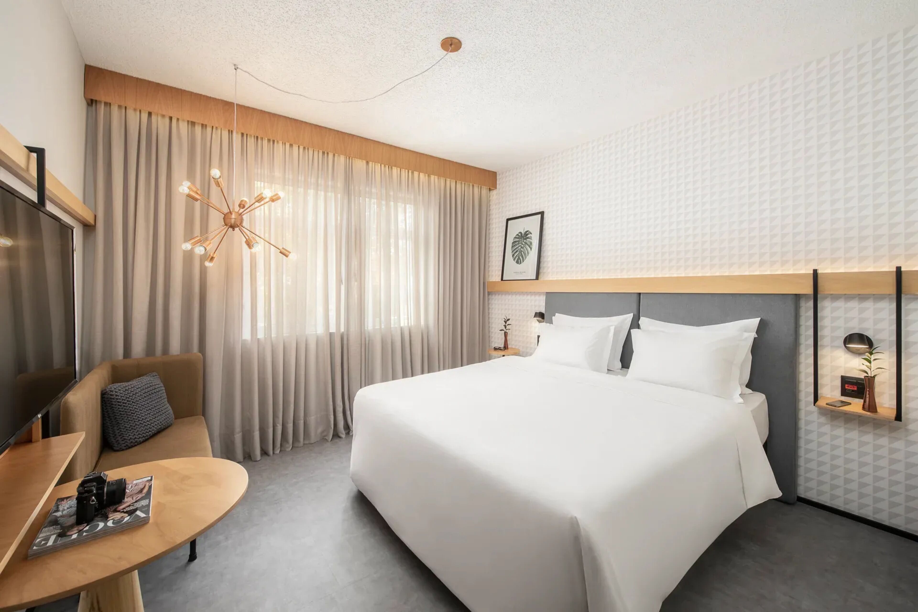 A hotel room with a large bed, a desk, a chair, and a TV.