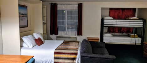 A hotel room with a bed, a couch, a desk, and a bunk bed.