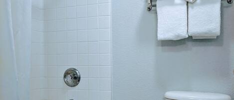 A bathroom with a bathtub, toilet, and a towel rack with towels.