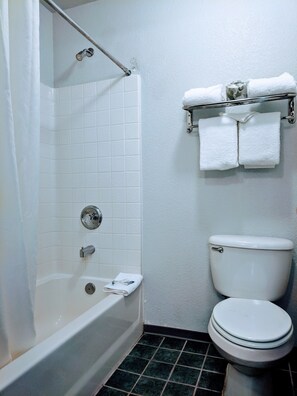 A bathroom with a bathtub, toilet, and a towel rack with towels.