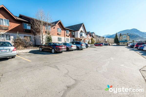 A parking lot with several cars and a row of buildings with a mountainous backdrop.